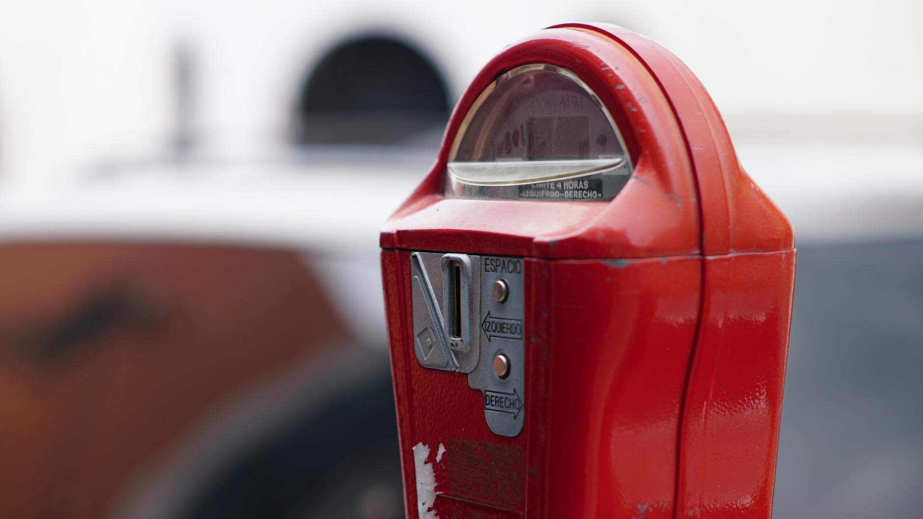 Close-up view of a red parking meter on a street in Juárez, Mexico.
