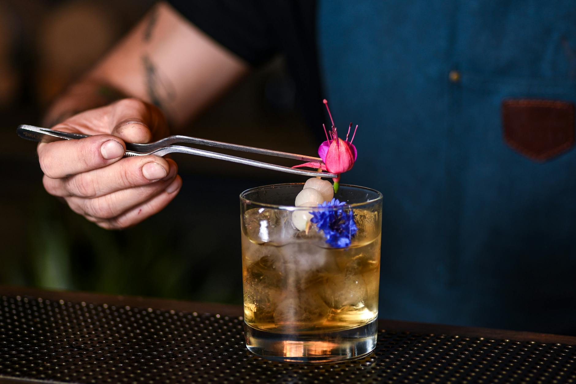 A bartender adds floral garnish to a cocktail in a trendy New York bar.